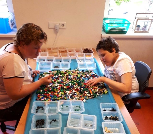 Twee jonge vrouwen zitten aan een tafel lego te sorteren