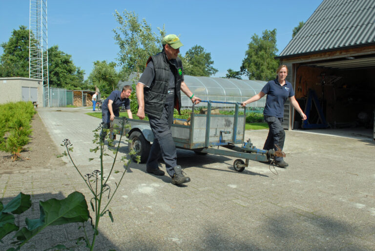 Medewerkers van De Sluis trekken een kar
