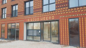 Ingang van de locatie Melsemaheerd met rode bakstenen met daarop de tekst Is gouw weerd
