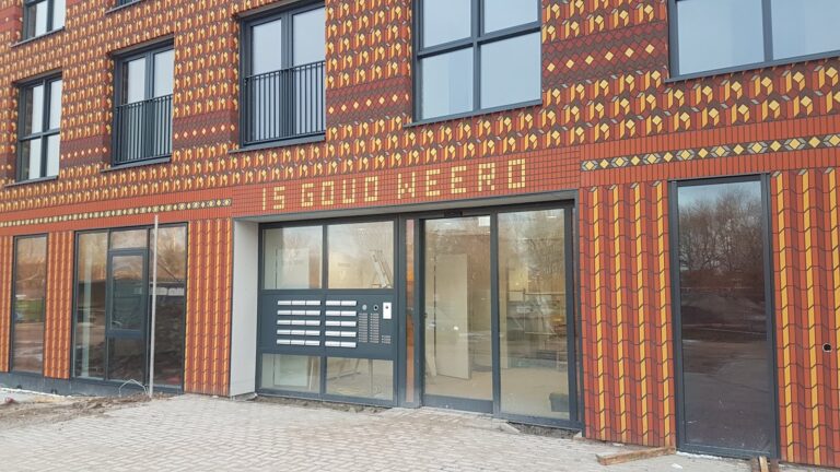 Ingang van de locatie Melsemaheerd met rode bakstenen met daarop de tekst Is gouw weerd