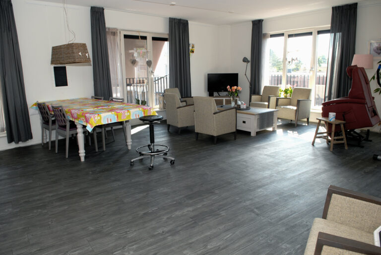 Grote huiskamer met een zithoek met televisie en een eethoek