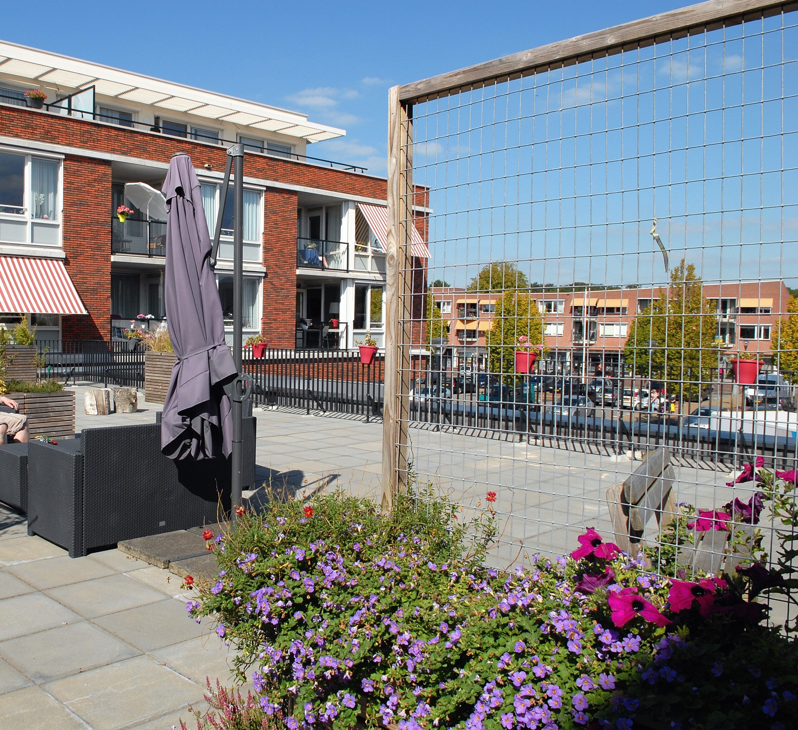 Dakterras bij appartementengebouw met bloemen en parasol