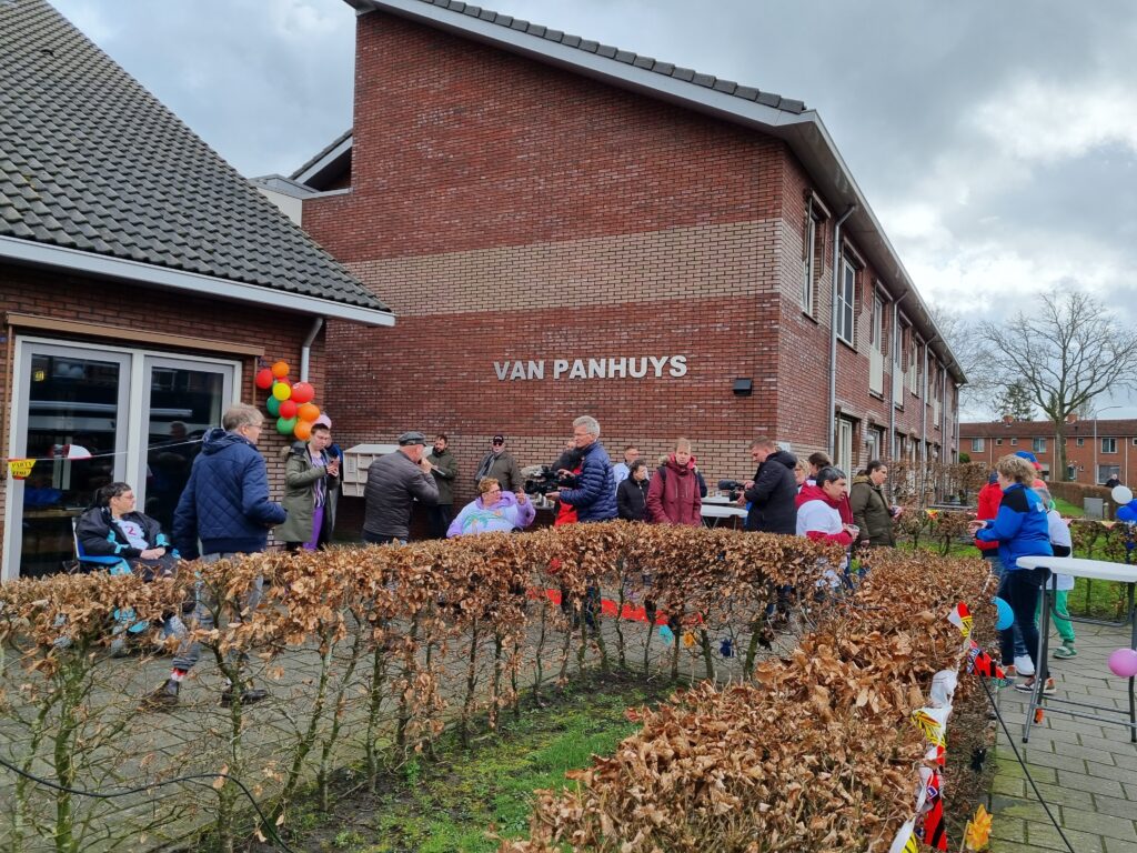 Grote groep mensen voor een gebouw waarop Van Panhuys staat geschreven
