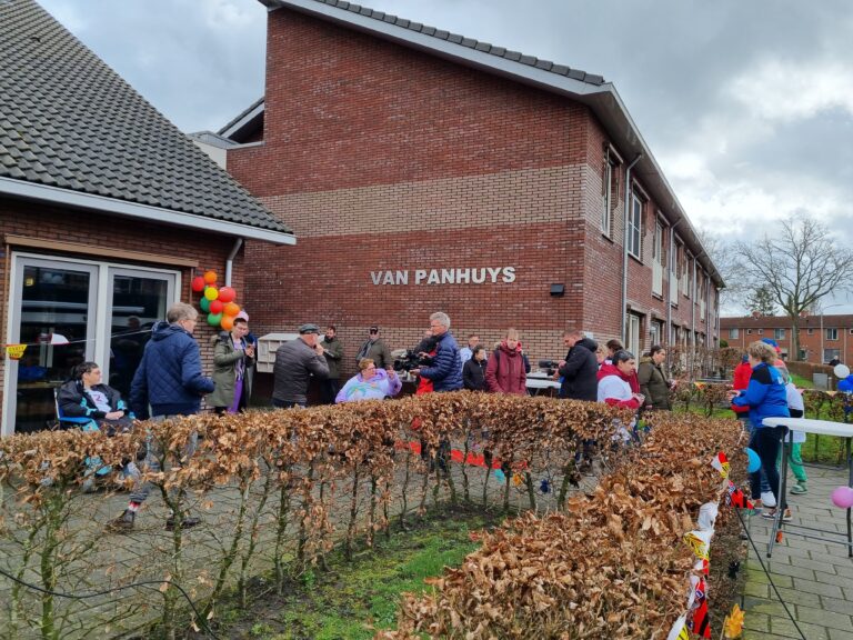 Grote groep mensen voor een gebouw waarop Van Panhuys staat geschreven