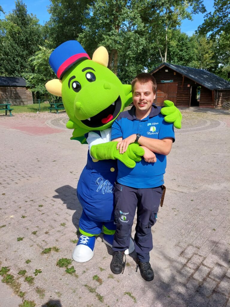 Jongen in blauw shirt wordt omhelst door mascotte Nino