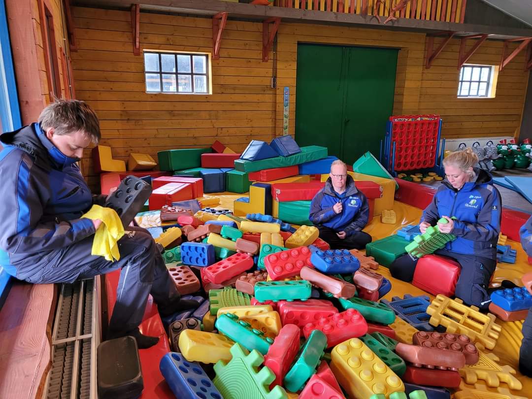 Drie personen die grote gekleurde legoblokken schoonmaken