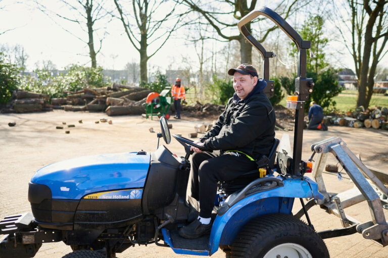 Man met pet op een blauwe zitmaaier