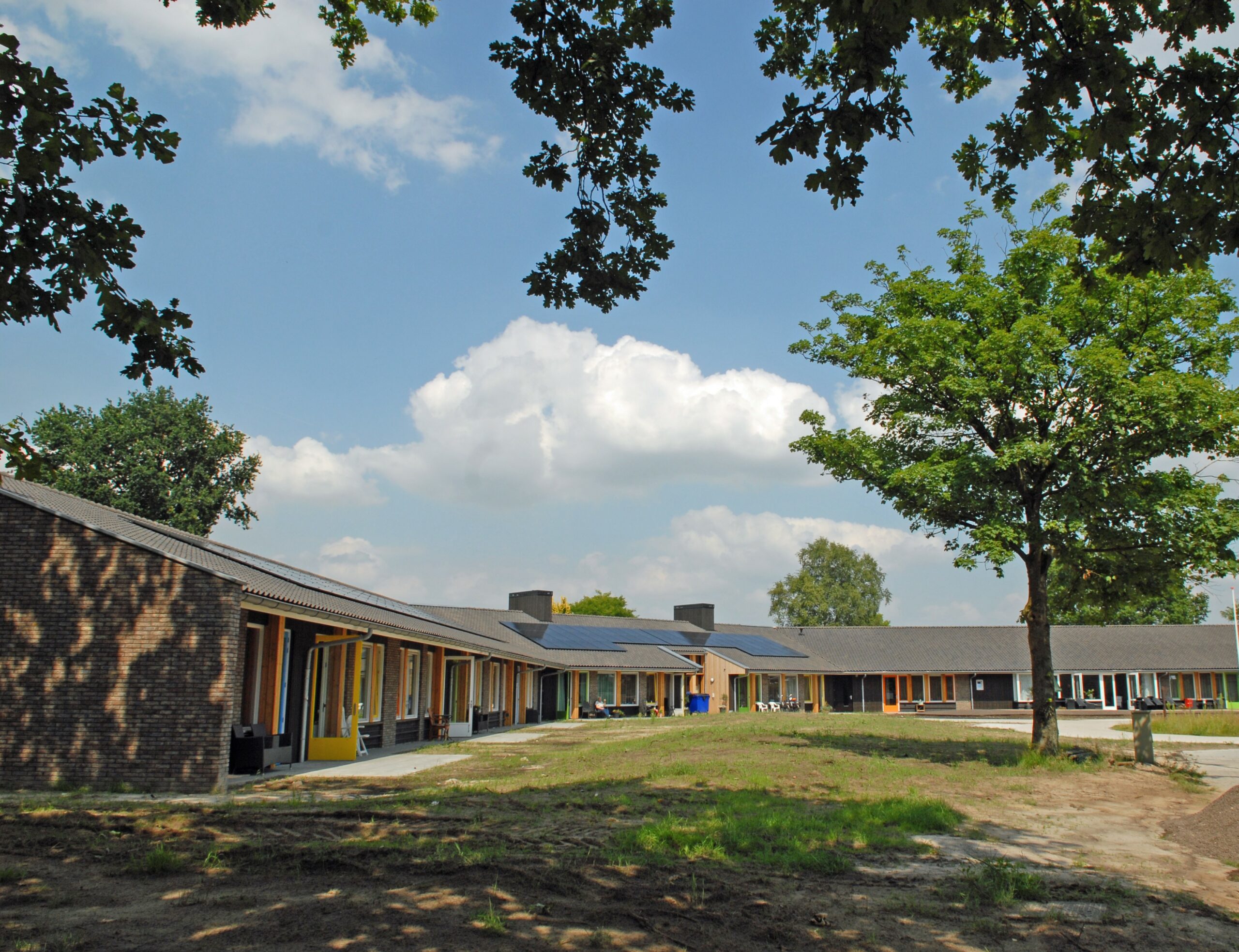 Allemaal woningen aan elkaar die in het rond gebouwd zijn met grasveld ervoor