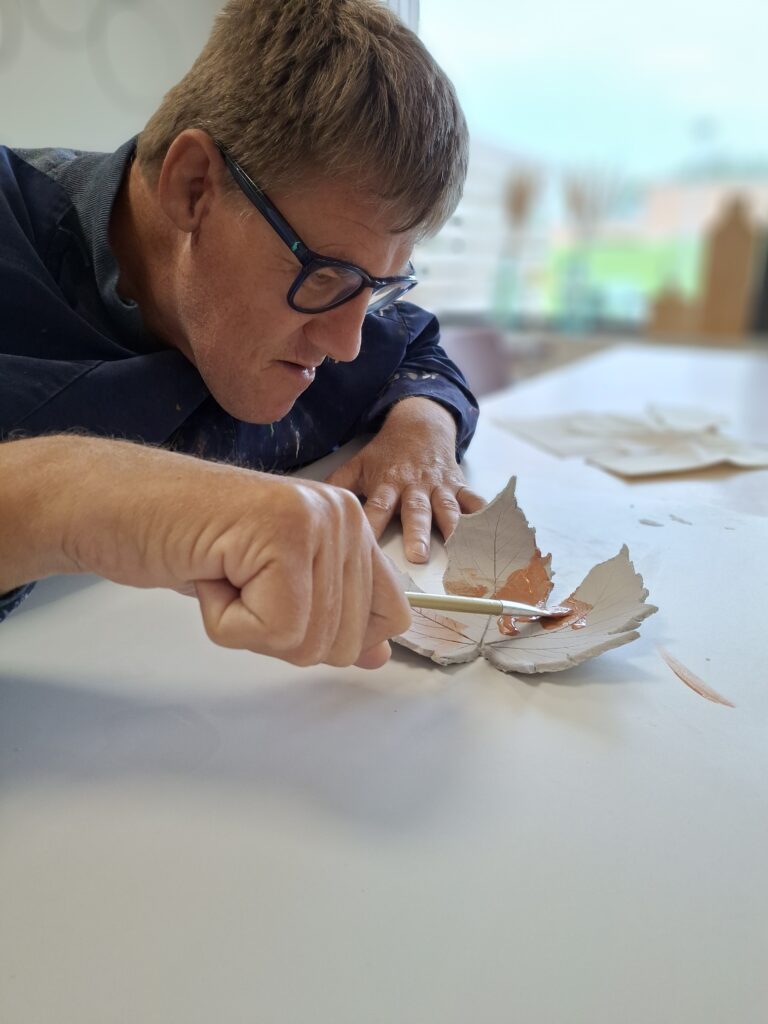 Man beschildert een blad van klei