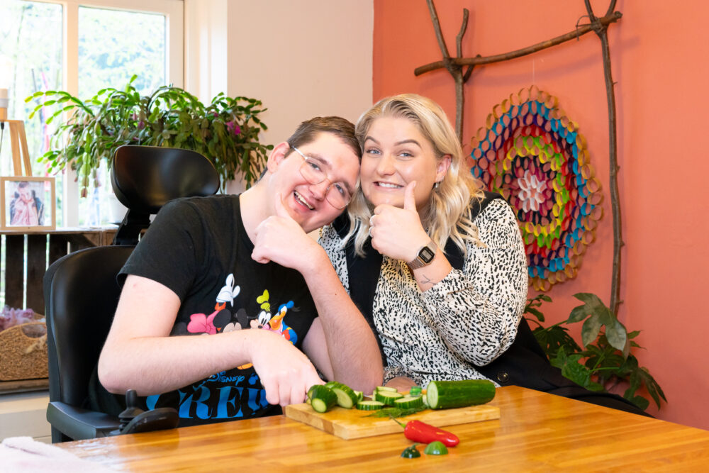 Jonge man en vrouw snijden een komkommer aan tafel
