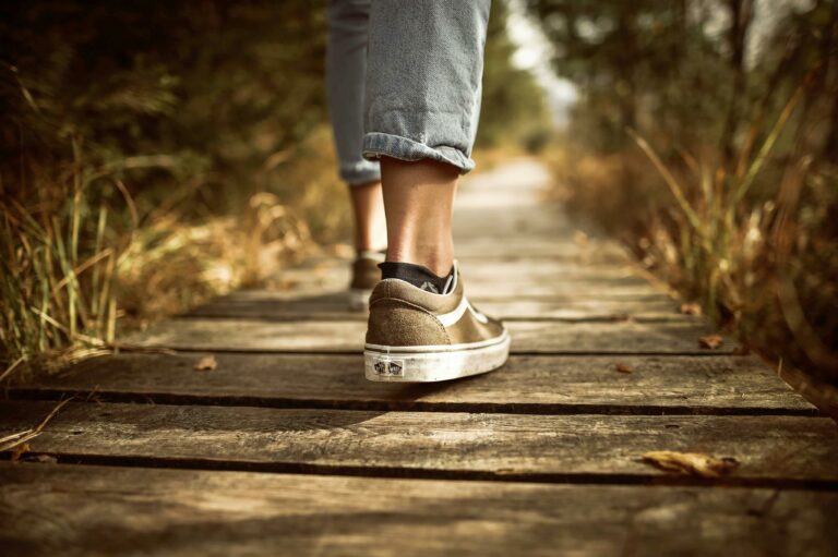 Iemand met gouden sneakers loopt over een houten brug