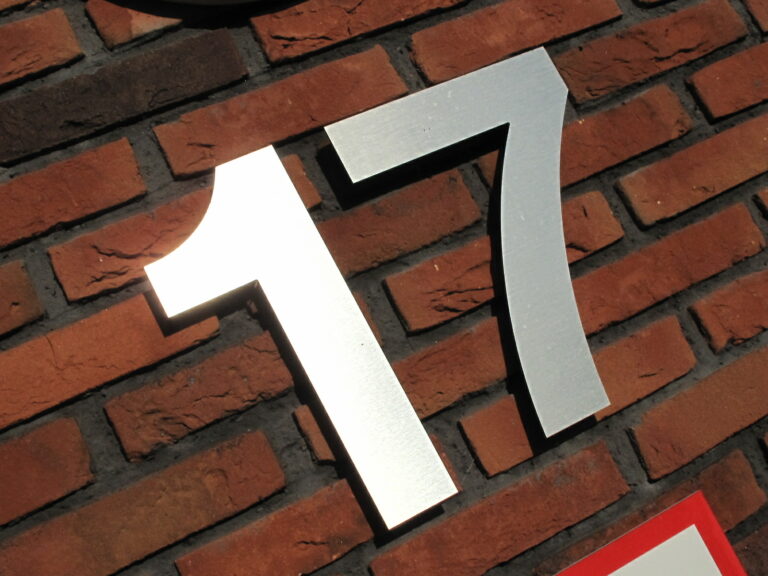 Zilveren cijfers 17 op een rode bakstenen muur