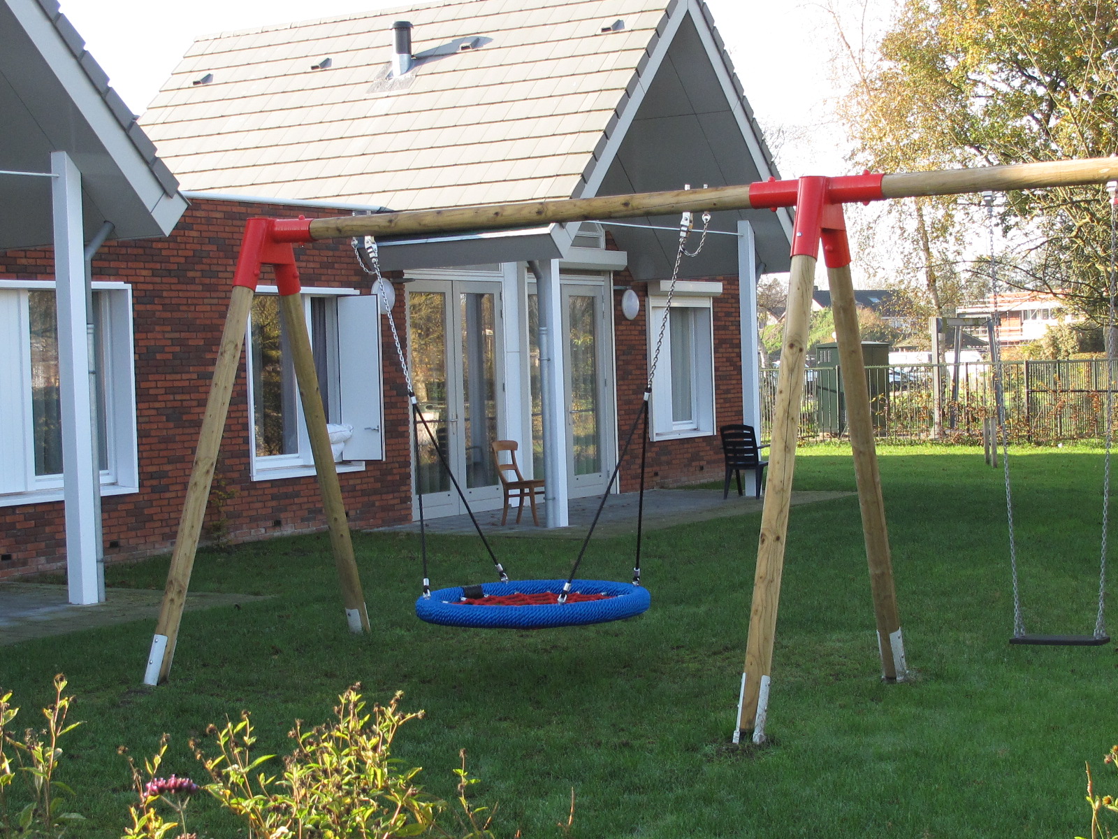 Ronde blauwe schommel en gewone schommel in tuin De Hanenbalk