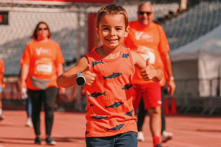 jongen in oranje shirt duimen omhoog vrouw en man lopen erachter
