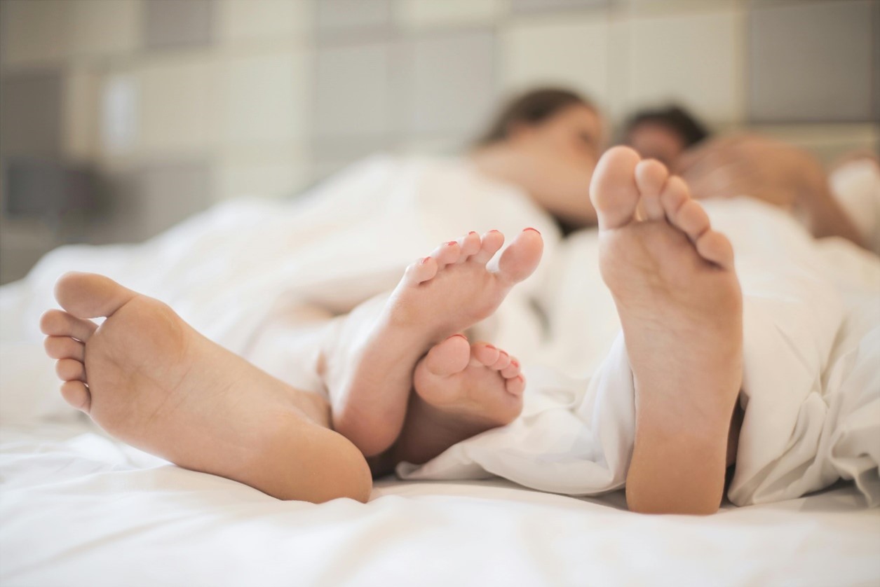 Twee grote voeten twee kleine voeten en twee grote voeten verstrengeld Twee mensen in bed