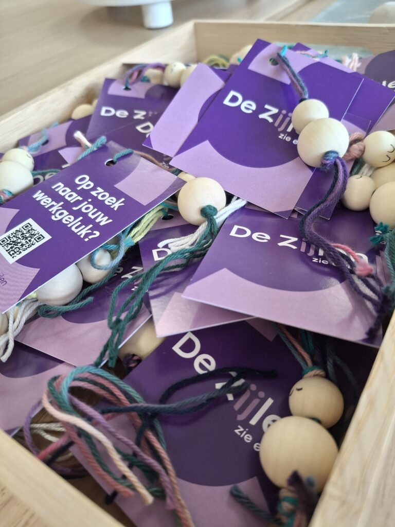 Paarse kaartjes met gelukspoppetjes eraan vast in een houten kisjte