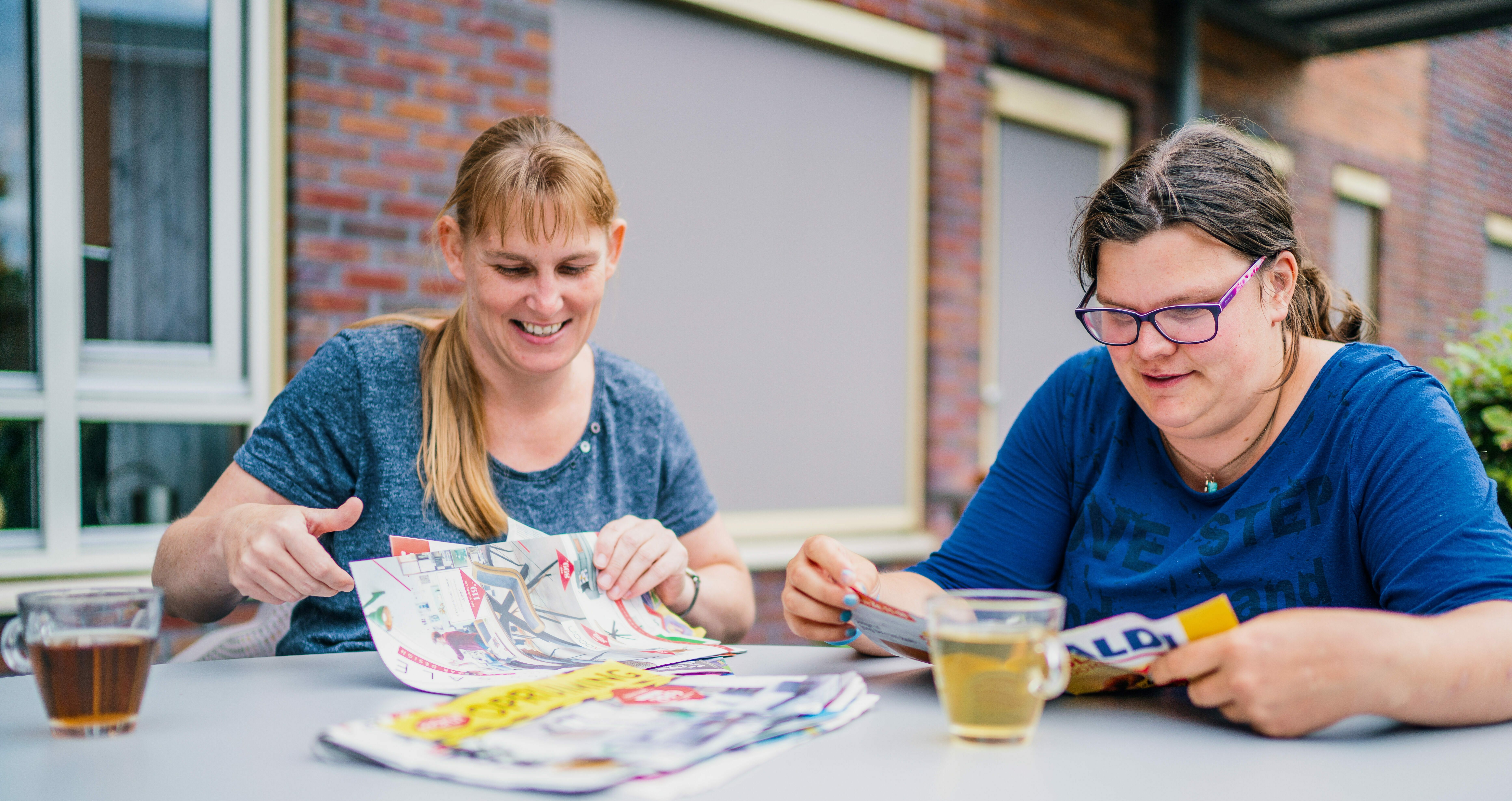 Twee jonge vrouwen aan tafel met thee lezen folders