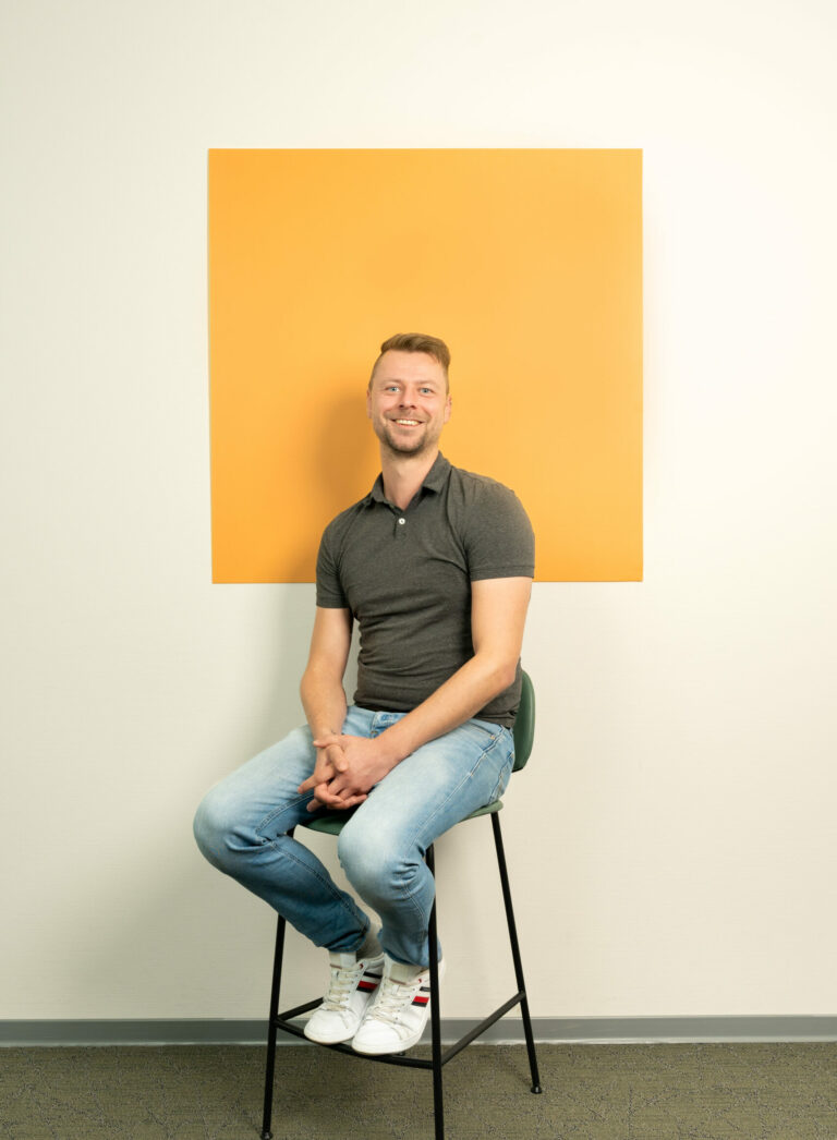 Man zit op een kruk voor een oranje/geel vierkant