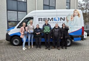 Twee jonge dames en vier personen in werkkleding staan voor een werkbus van Remon wateronderhanders