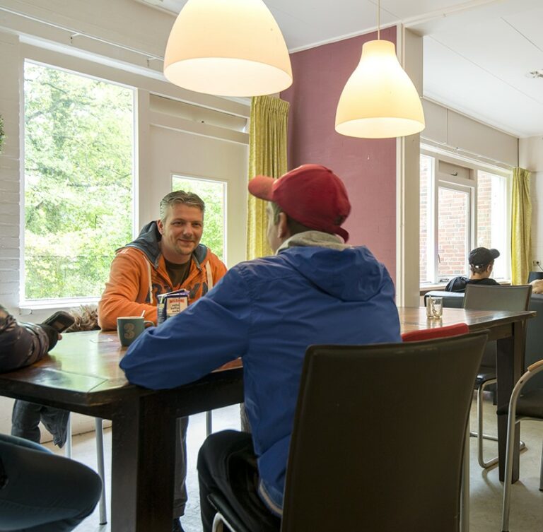 Twee mannen zitten aan een tafel koffie te drinken