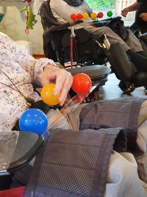 Zittend persoon blauw geel en rood balletje op schoot