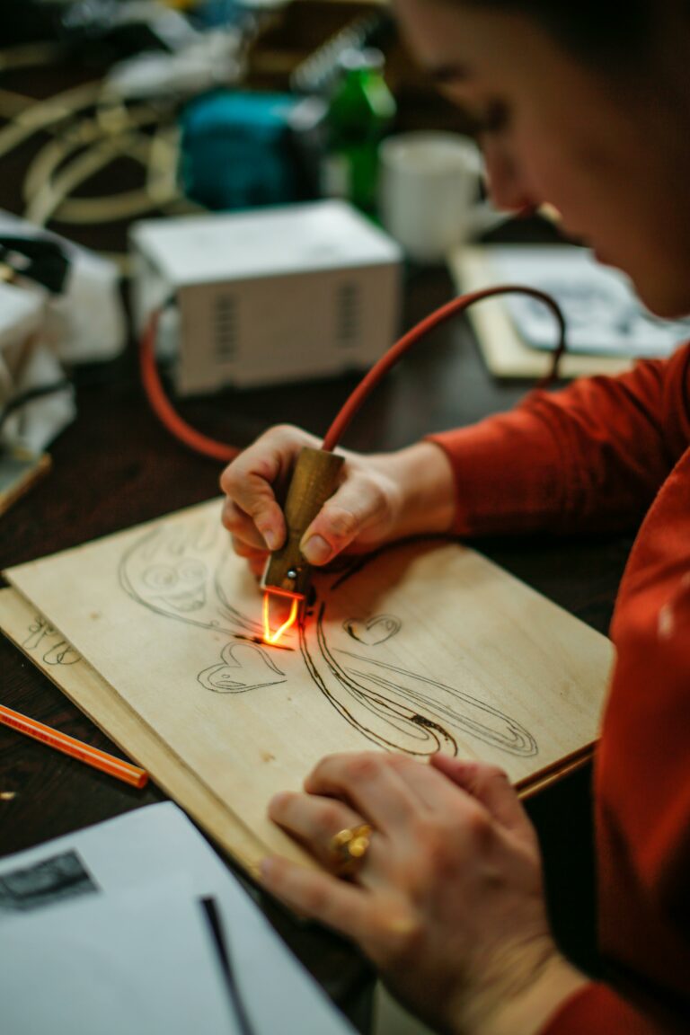 Vrouw in rode trui bewerkt een houten plankje met een houtbrander