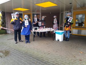 Mensen rondom kraampje voor winkel met bord voor zich