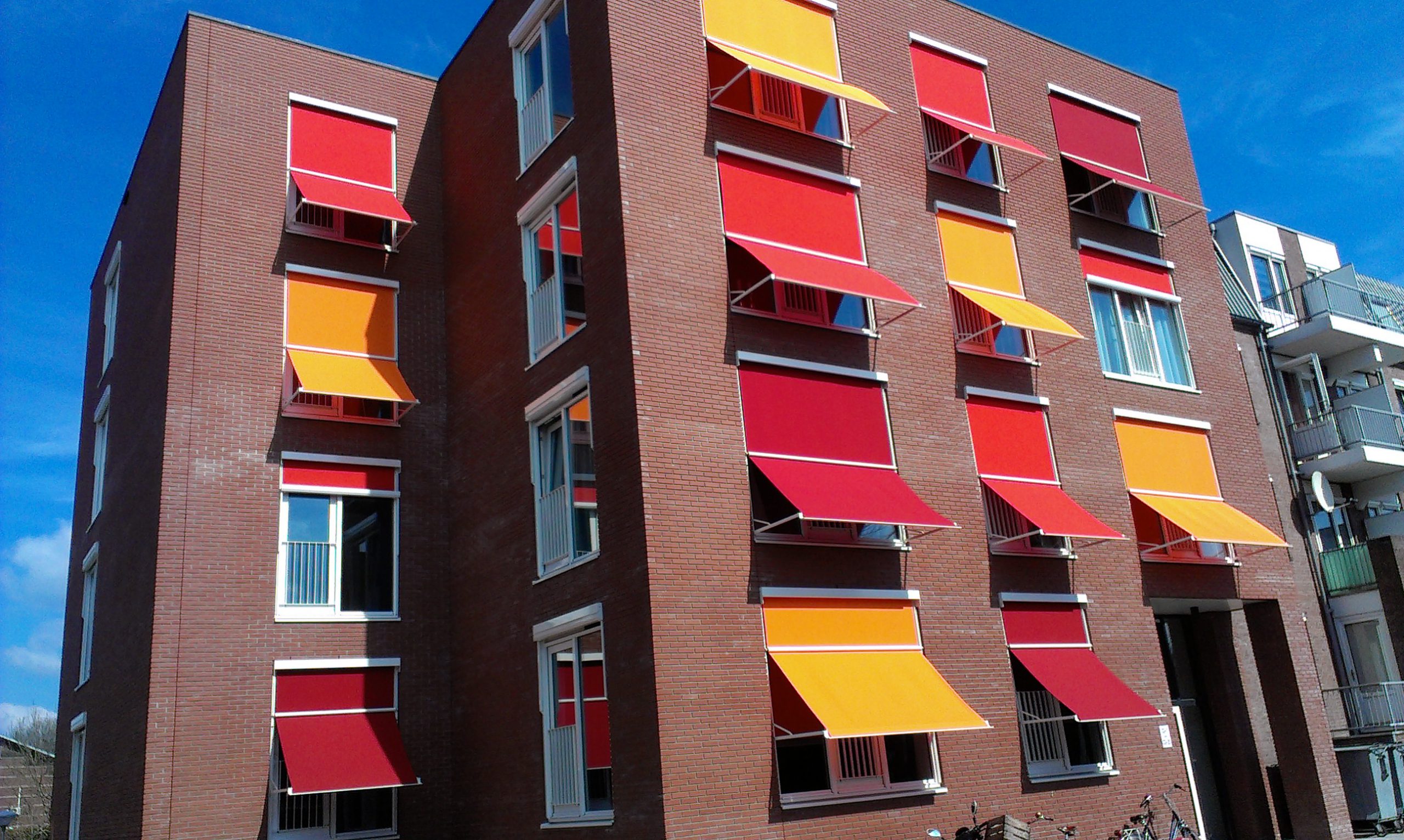 Appartementengebouw rode en oranje windschermen