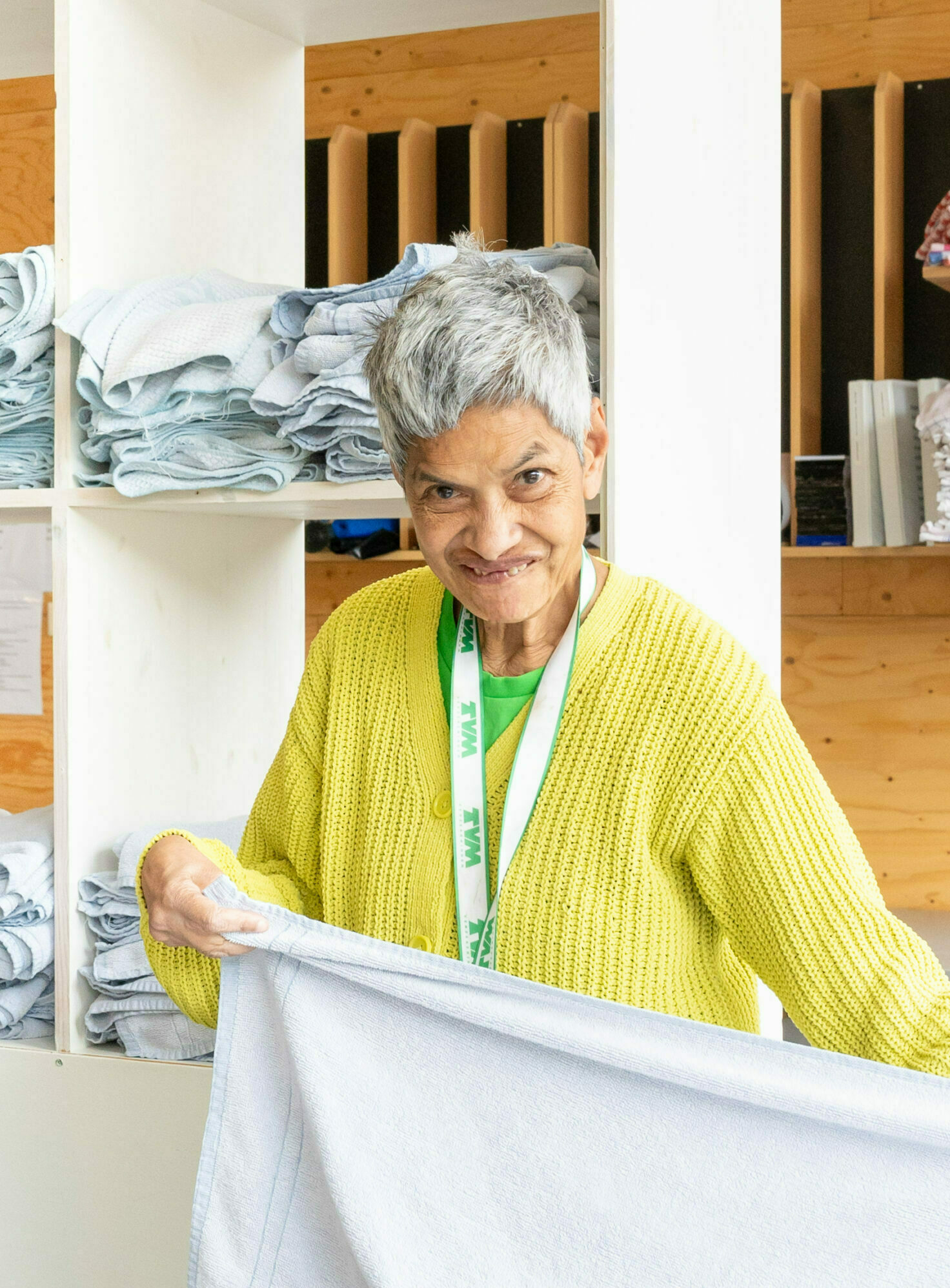 Vrouw in geel vest vouwt een witte handdoek op