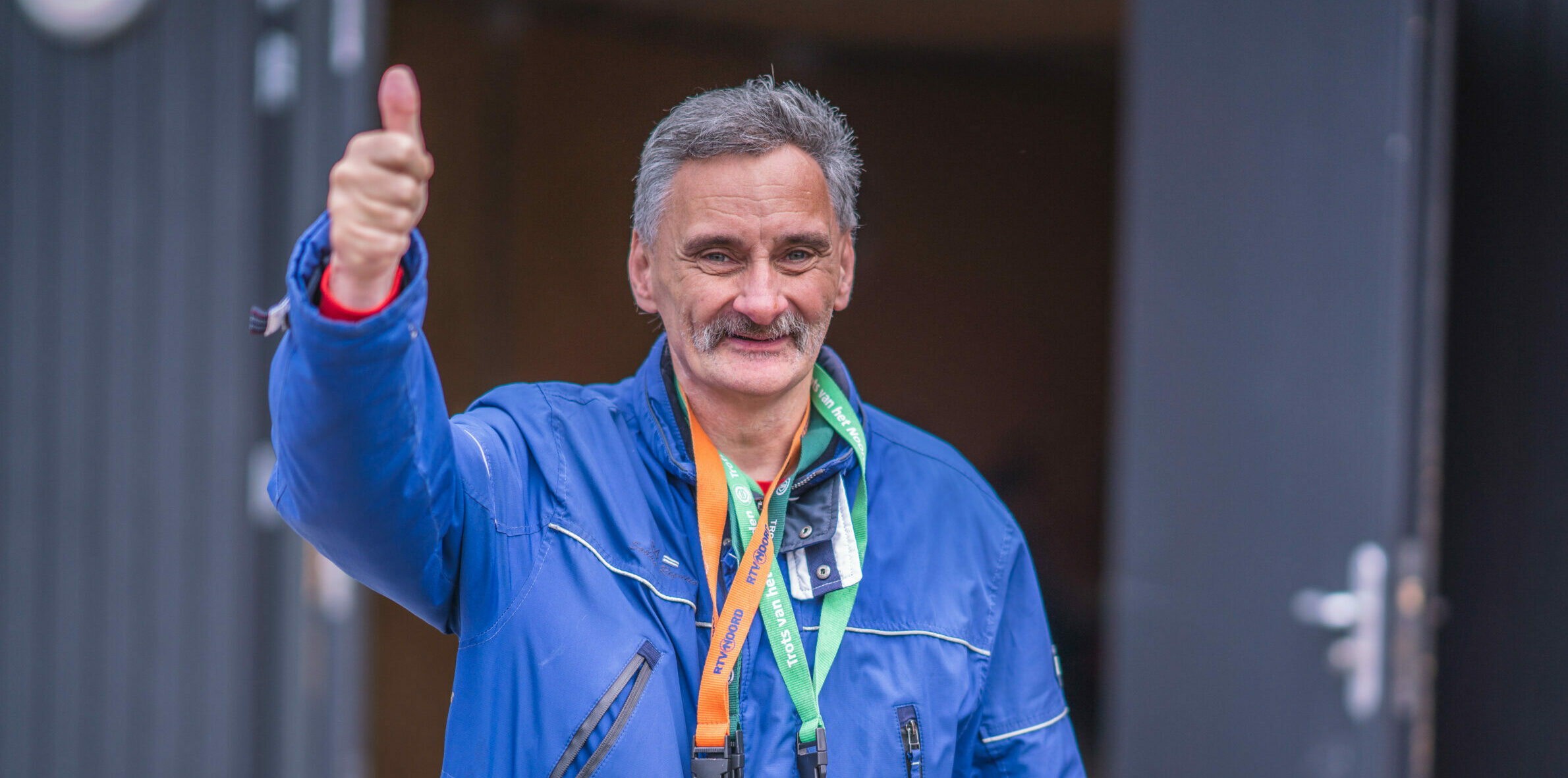 Blije man in blauwe jas steekt duim onhoog