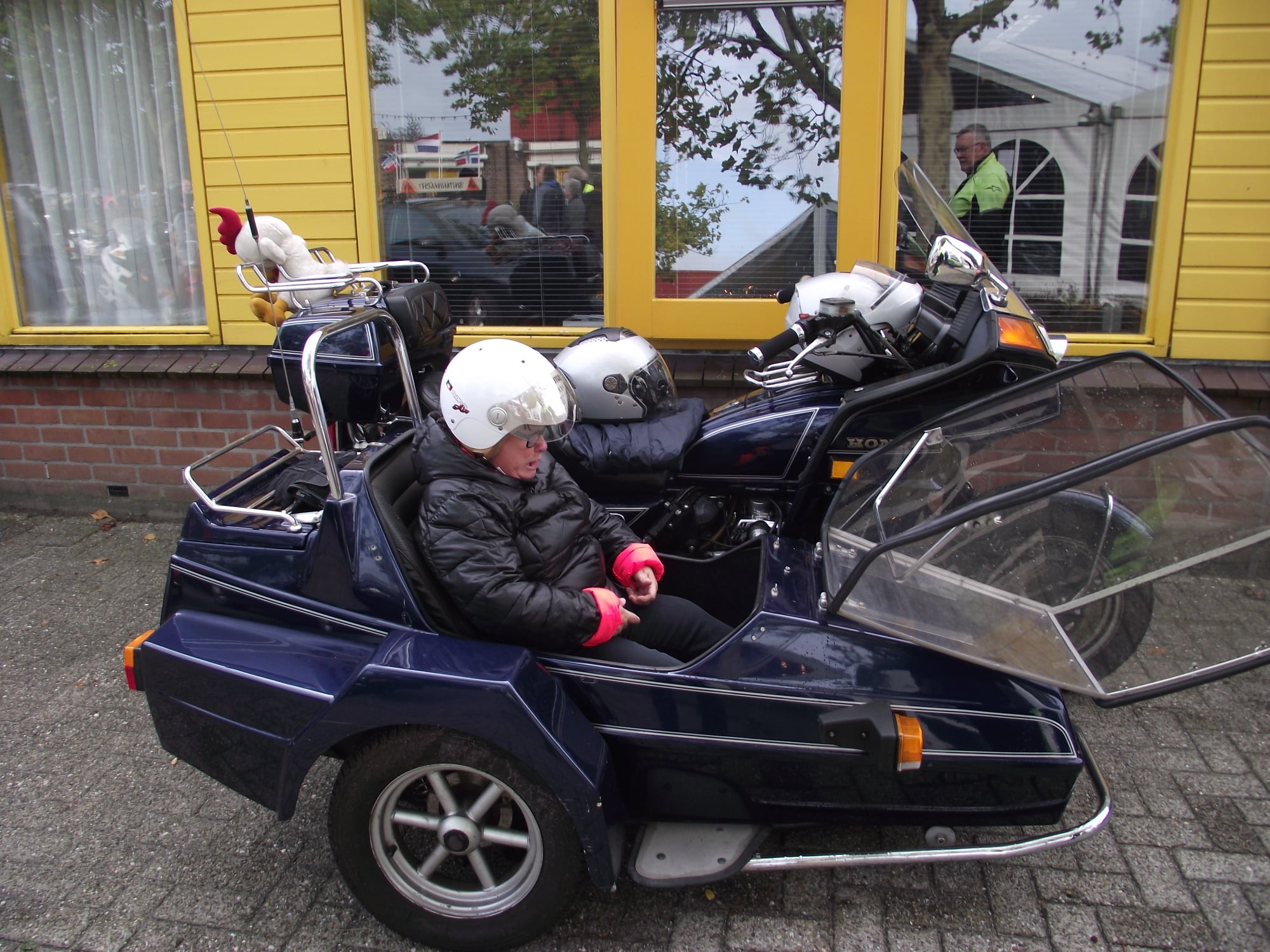 Grote blauwe Honda motor met zijspan waar vrouw in zit met witte helm op