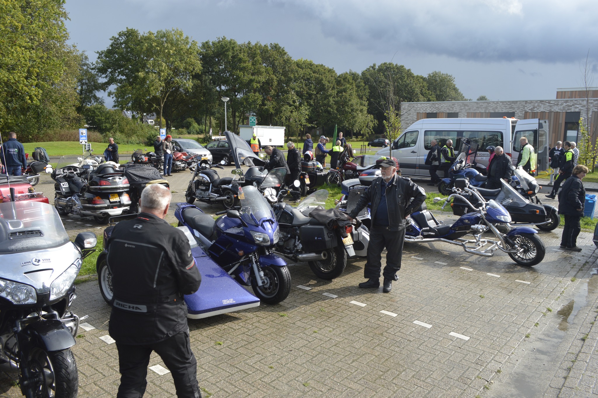 Allemaal stoere mannen in motorkleding staand bij motoren en motoren met zijspan op een parkeerplaats