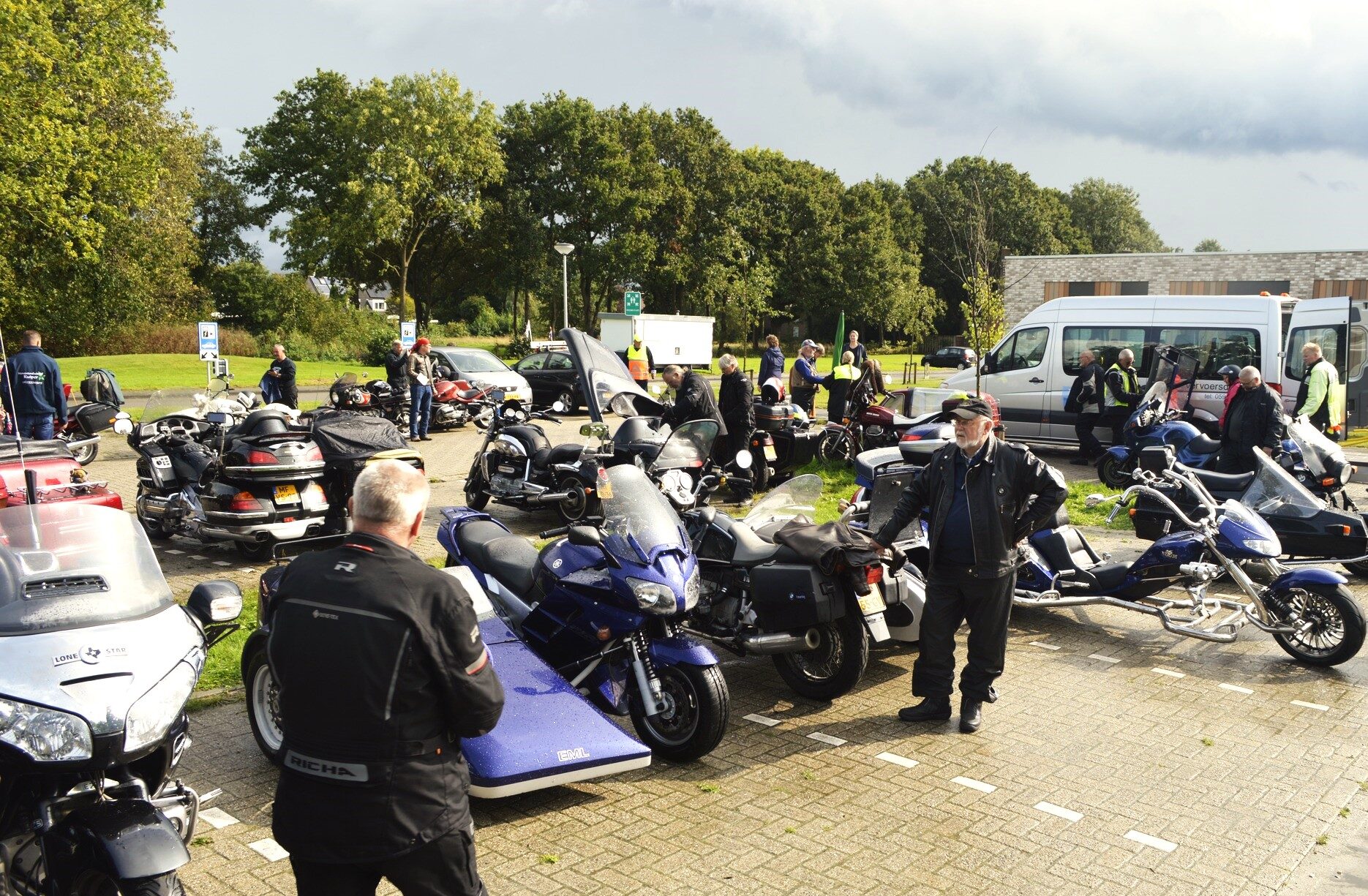 Veel zijspanmotoren en rijders op een parkeerplaats