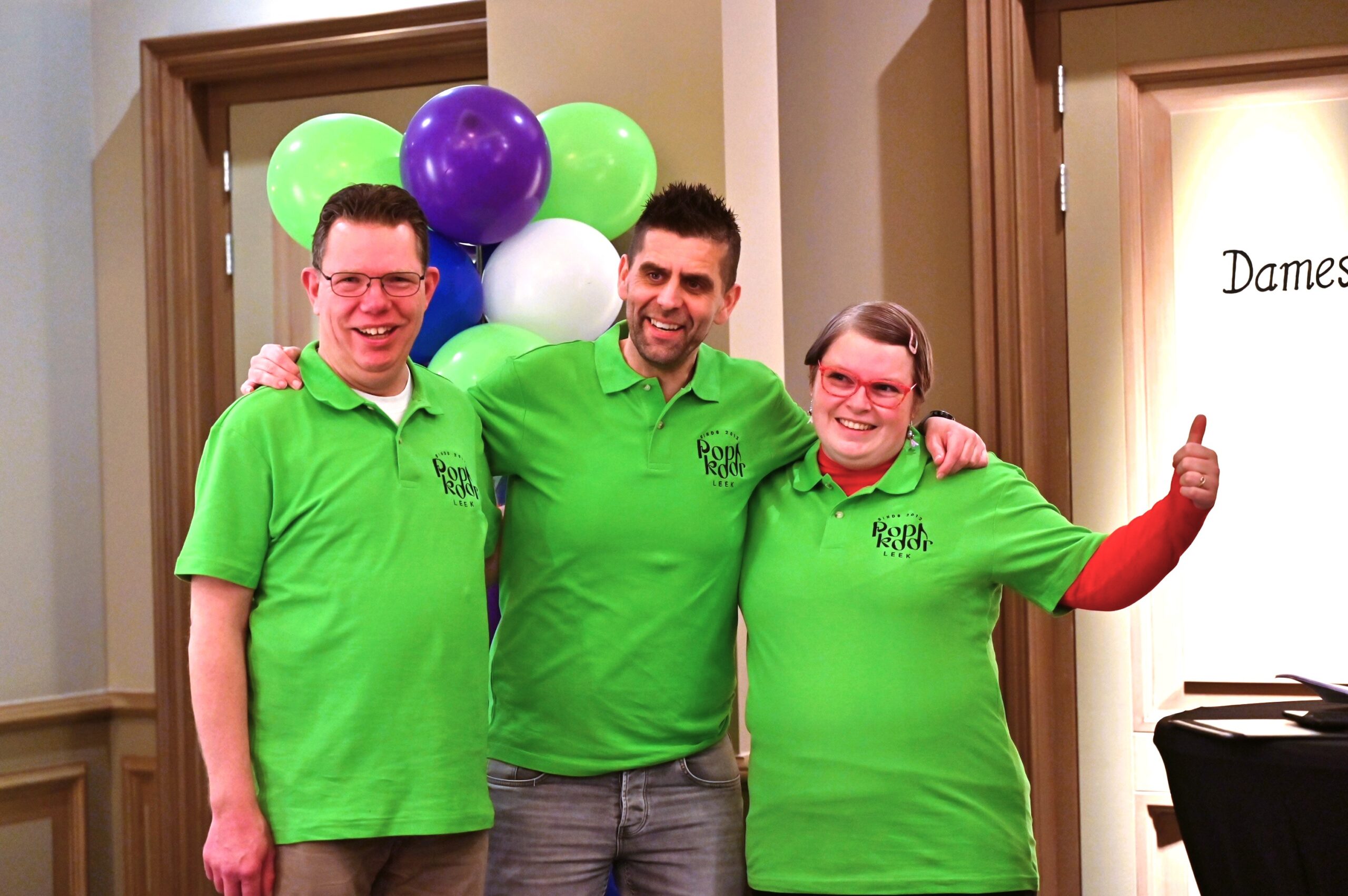 3 mensen in groene T-shirts poseren lachend voor de foto